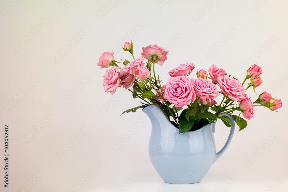 Pink flowers in blue jug. Roses in jug.