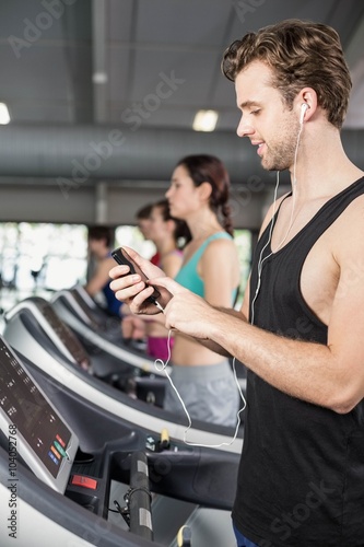Smiling muscular man on treadmill listening to music © WavebreakMediaMicro