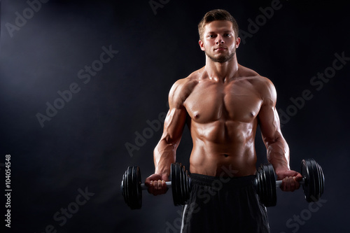 He is a winner. Horizontal studio shot of a handsome shirtless muscular man working out with heavy dumbbells