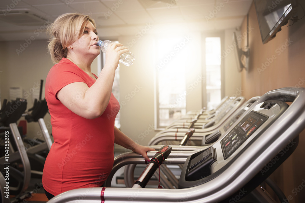Woman drinking water during the running at the gym Woman drinking water during the running at the gym