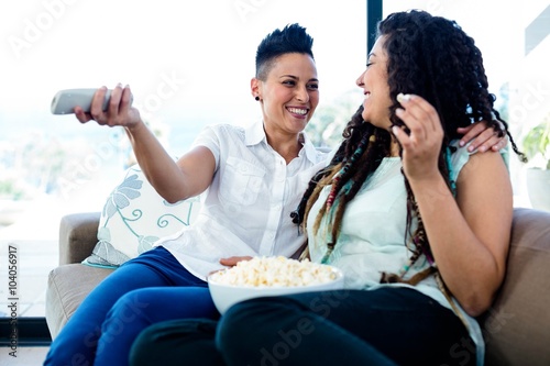 Lesbian couple watching television with a bowl of popcorn