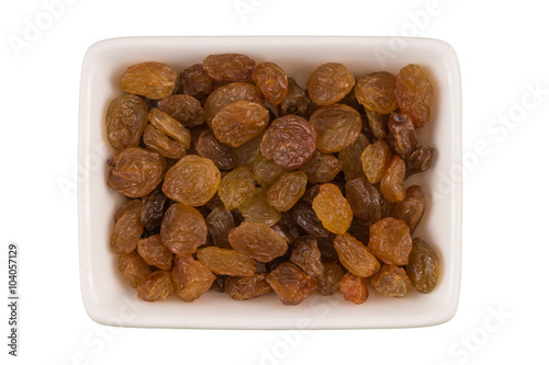 Bowl of brown raisins isolated on white background