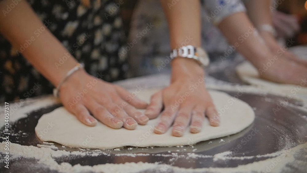 Woman hands kneading the dough on the metal table full of flour Woman hands kneading the dough on the metal table full of flour