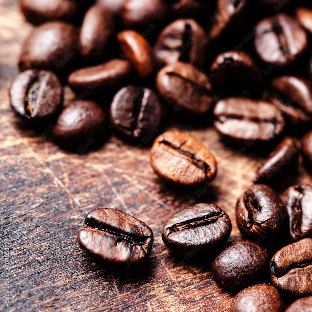 Naklejka premium Coffee beans on grunge wooden background