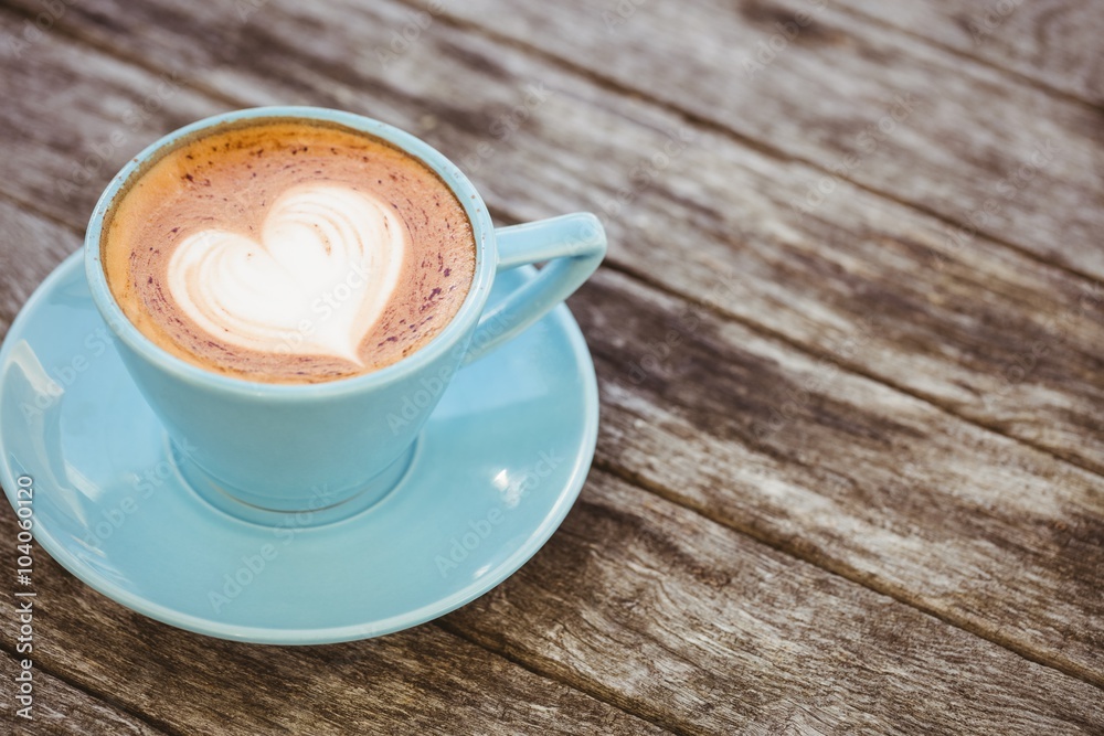 Cup of cappuccino with coffee art on wooden table Cup of cappuccino with coffee art on wooden table