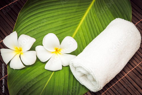 spa concept. white towel and plumeria flowers on the bamboo mat