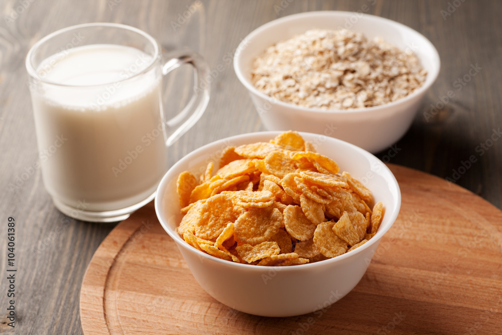 Oatmeal, cornflakes and glass of milk on wooden table Oatmeal, cornflakes and glass of milk on wooden table