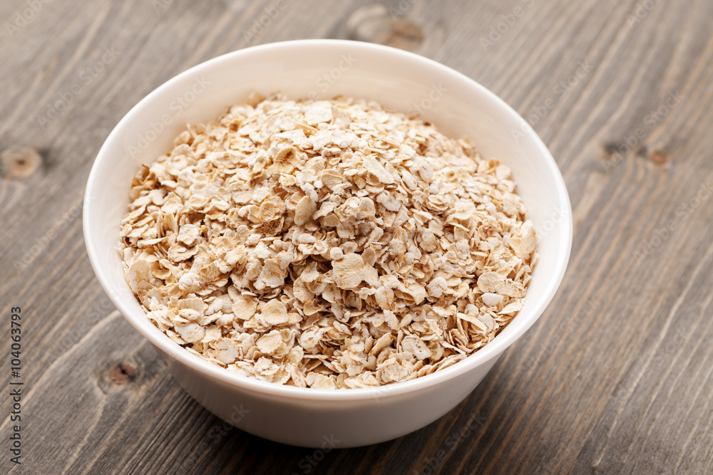 Oatmeal in white ceramic bowl on wooden table Oatmeal in white ceramic bowl on wooden table
