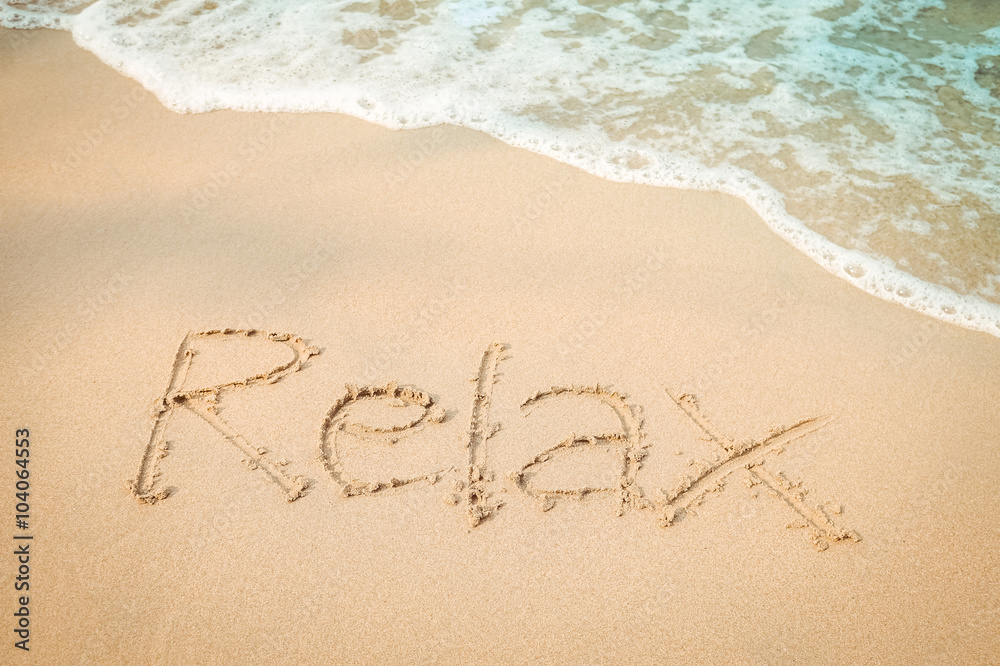 Relax message hand writing on the sand beach