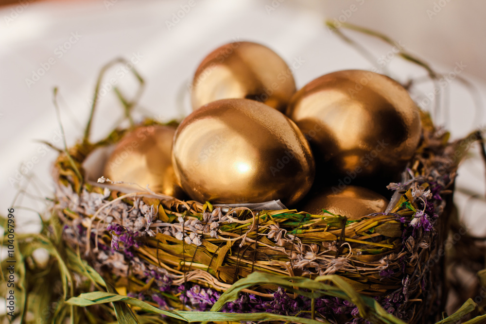 Golden easter eggs in nest on white wooden background Golden easter eggs in nest on white wooden background