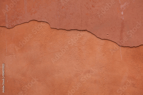 Old terracotta painted stucco wall with cracked plaster. Backgro photo