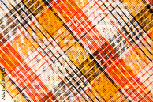The texture of white checkered, orange, red, black cotton fabric