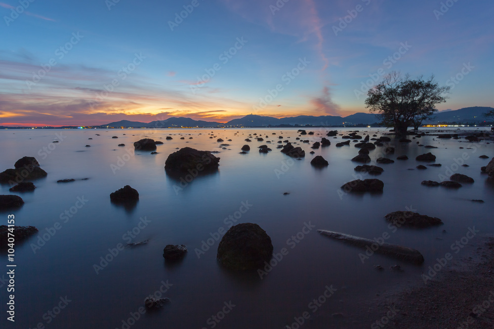 Beautiful sunset at twilight sky, silhouette stones and trees at Khao Khad, Phuket, Thailand