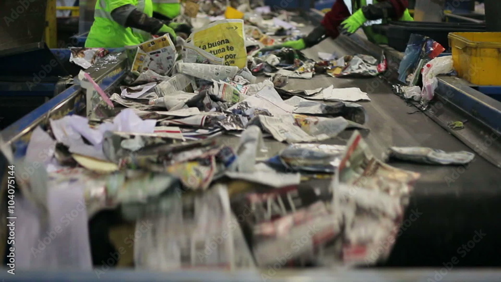 Workers sorting paper and plastic on a recycling belt