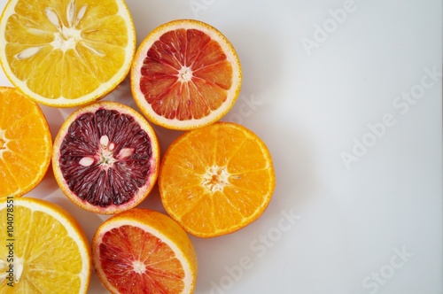 Ruby red blood oranges  navel oranges  and clementines cut in half on a white platter