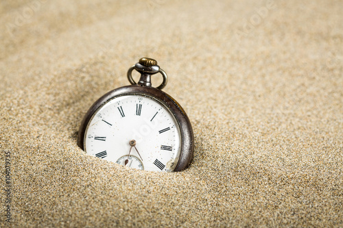 Une vieille montre à gousset à demi enterrée dans le sable photo