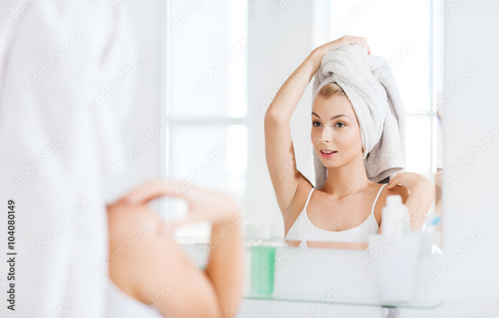 happy young woman with towel at mirror in bathroom happy young woman with towel at mirror in bathroom