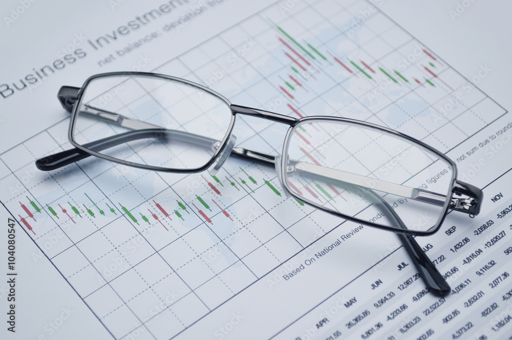 Glasses on stock market graph, financial concept Glasses on stock market graph, financial concept
