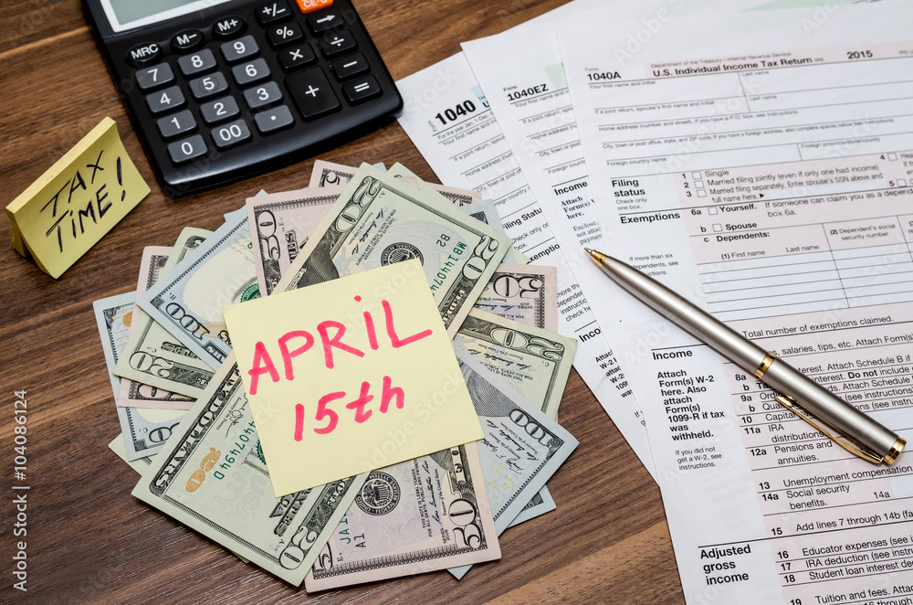 Obraz premium 1040 tax form with sticky note of april 15, us dollar and calculator
