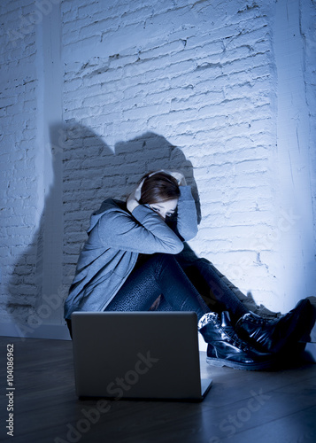 scared female teenager with computer laptop suffering cyberbullying and harassment being online abused