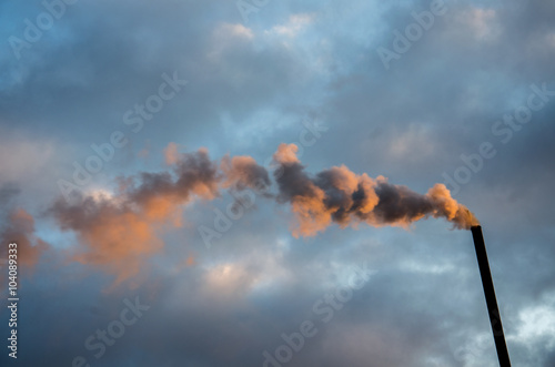 Color photograph of industrial buildings at sunset. smokestacks contributing to the pollution in the air. dense smoke background. Smoke raising from a chimney. Tube and smoke