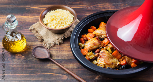 Tagine with cooked chicken and vegetables Wooden background Copy space photo