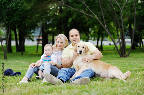 family plays with the retriever in the grass