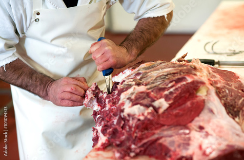Butcher cutting up a large slab of raw meat