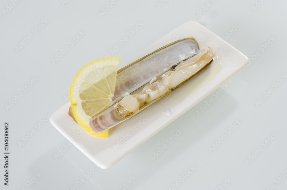 White dish of grilled razor clams with lemon White dish of grilled razor clams with lemon