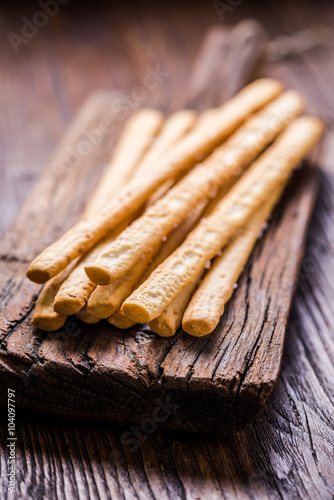 Bread sticks with salt on wooden board