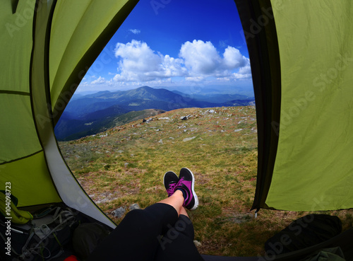 Woman lying in a tent with coffee ,view of mountains and sky
