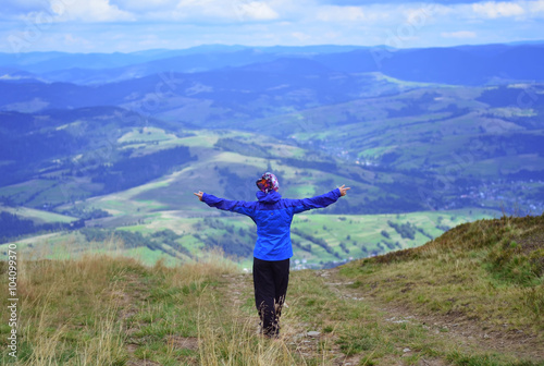 Young woman on the mountain with raised hands