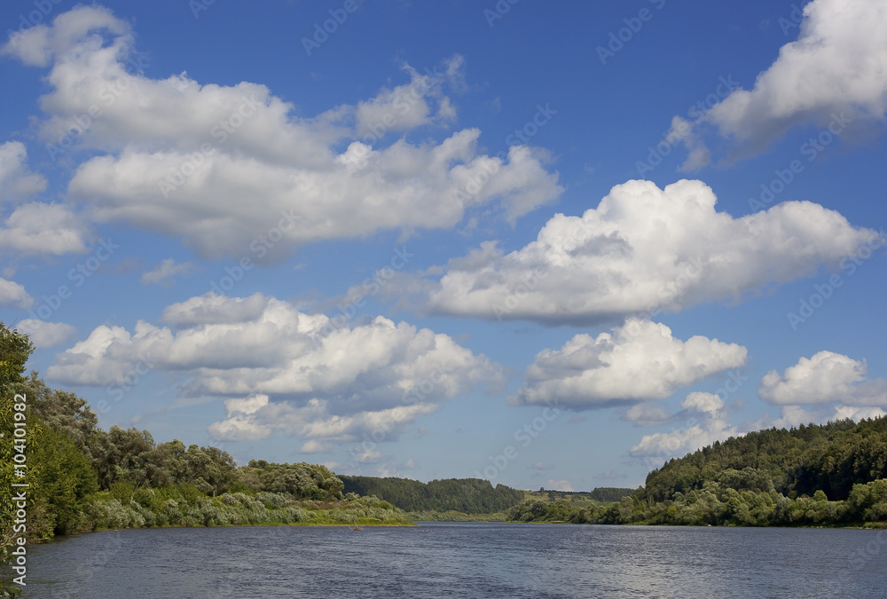 Summer landscape with river and clouds over the water.