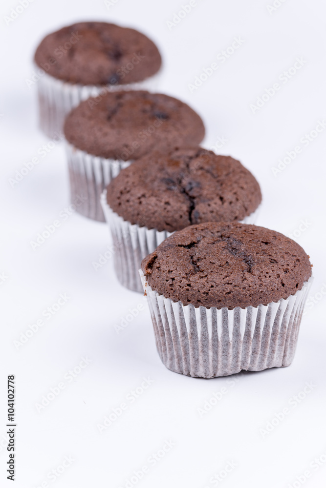 Brown chocolate muffins arranged over white background Brown chocolate muffins arranged over white background