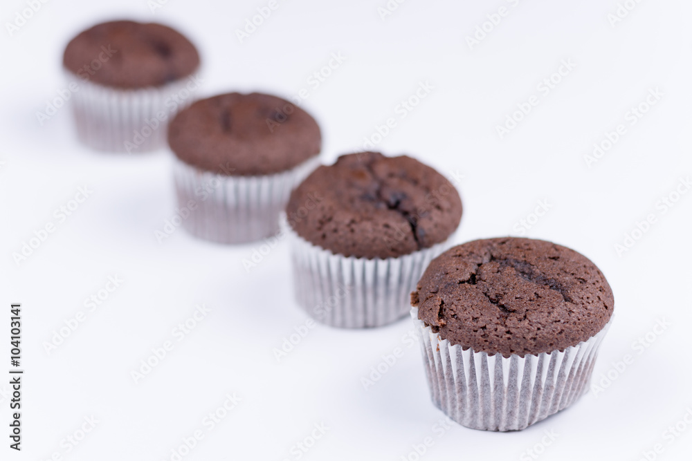 Brown chocolate muffins arranged over white background Brown chocolate muffins arranged over white background