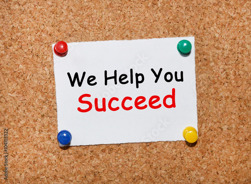 The phrase We Help You Succeed typed on a white piece of note paper and pinned to a cork notice board