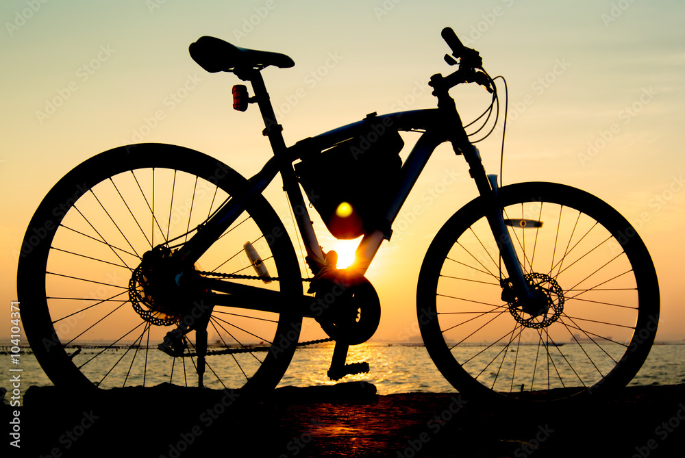 Silhouette of mountain bike at sea with sunset sky background Silhouette of mountain bike at sea with sunset sky background