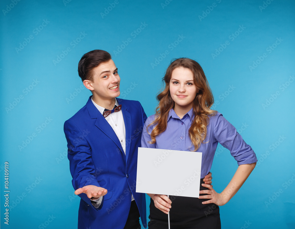 Smiling hipster couple in the jeans and jacket with the sheet in the studio Smiling hipster couple in the jeans and jacket with the sheet in the studio