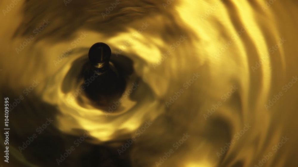Orange Water Drop - A high quality, super slow motion in camera macro shot of a single orange water drop falling into frame, producing silky waves and ripple effects.