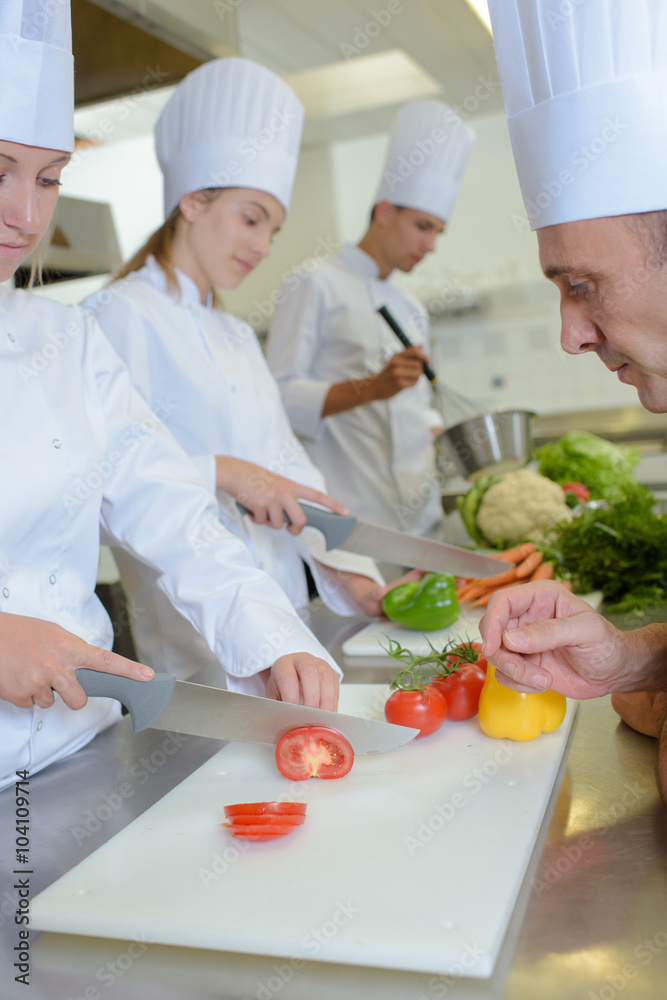 Chef watching students chop vegetables