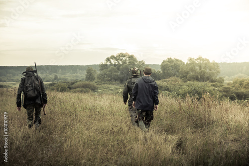 group of people  going up in the early morning in a rural field through the tall grass during hunting © splendens