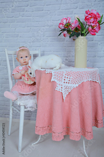 little 8 months girl in a rose knitting dress sitting on a chair with white rabbit like Alice in wonderland, mad tea party, Healthy kids, happy people, childcare concept photo