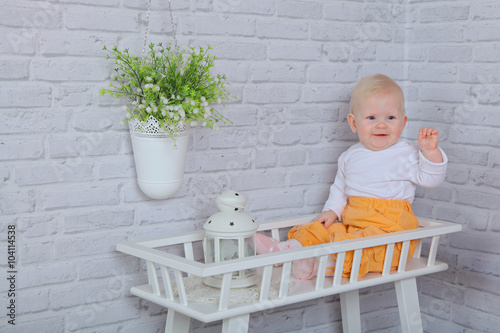ittle 8 months girl sitting on a white bench with white vintage lamp, Healthy kids, happy people, childcare concept photo