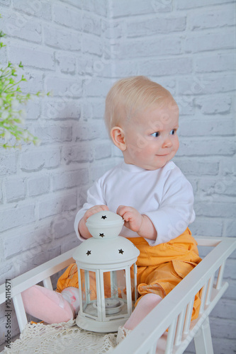 ittle 8 months girl sitting on a white bench with white vintage lamp, Healthy kids, happy people, childcare concept photo