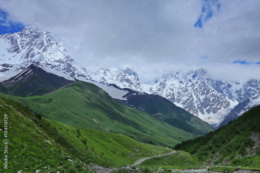Fototapeta premium Beautiful view of rural alpine landscape. Sunny hills under cloudy sky. Upper Svaneti, Georgia, Europe. Caucasus mountains. Beauty world.