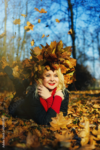 High fashion blonde girl with the red lips in the wreath of leaves and in the fallen leaves in the park outdoor
