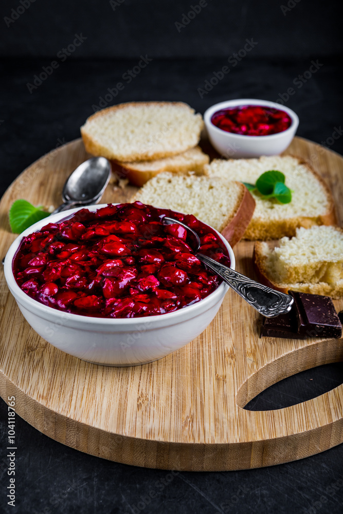 Cherry jam in white bowl and on yeast cake Cherry jam in white bowl and on yeast cake