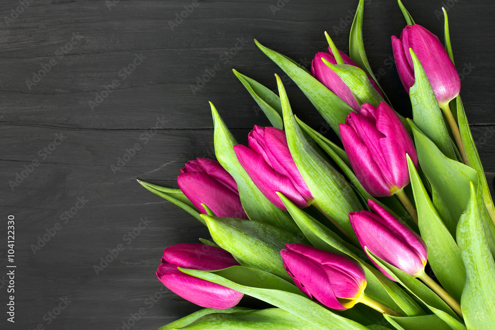 Fototapeta premium Bukiet różowych tulipanów leżący na czarnych deskach. 