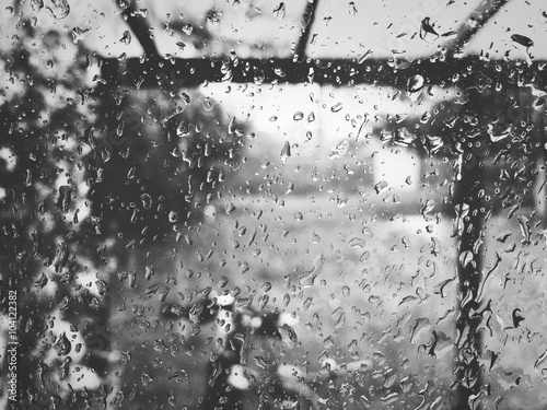 Moody window glass full of raindrops in black and white photo