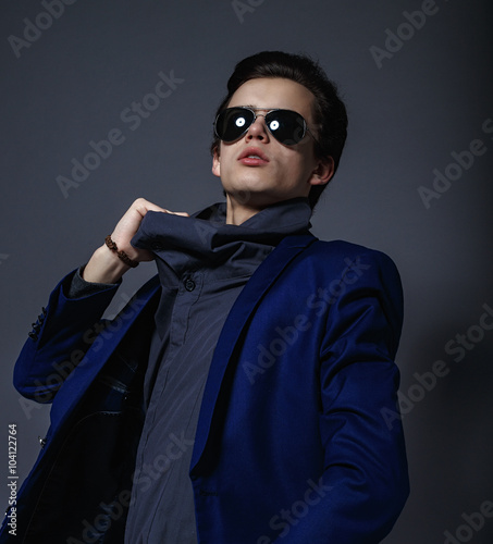 Vogue handsome man in the jacket and sunglasses in the studio